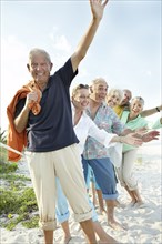 Senior friends waving on beach