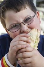 Boy eating sandwich outdoors