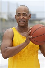 Senior man playing basketball outdoors