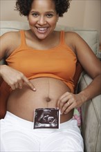 Pregnant woman showing sonogram by belly