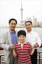 Three generations of men smiling by city skyline