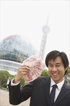 Chinese businessman holding wad of money