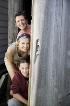 Family peeking out from behind door