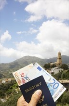 Passport and Euros overlooking rural landscape