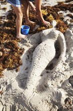 Mermaid sculpture in sand on beach