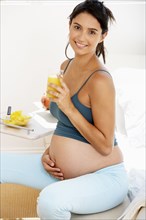 Pregnant Hispanic woman drinking fruit juice