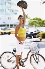 Pregnant Hispanic woman riding bicycle on city street