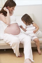 Caucasian girl drawing on mother's pregnant belly
