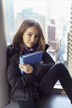 Girl holding binder on windowsill