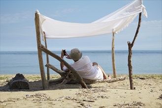 Woman relaxing under homemade shade on beach