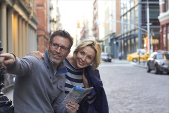 Caucasian couple holding map in city