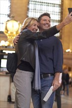 Caucasian couple taking cell phone selfie in Grand Central Station