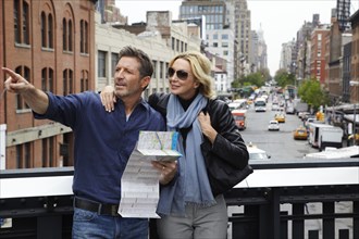 Caucasian couple holding map in city