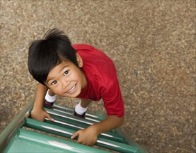 Asian boy climbing ladder on playground