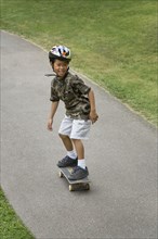 Asian boy skateboarding downhill