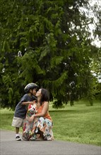 Asian boy with skateboard kissing mother