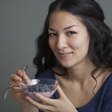 Mixed race woman eating yogurt and fruit