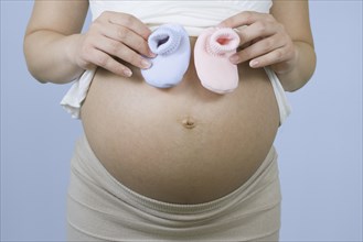 Pregnant Chinese woman holding pink and blue booties