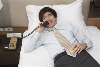 Chinese businessman on telephone in hotel room