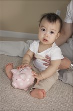 Chinese father and baby with piggy bank