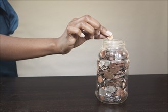 Black woman putting coin into jar