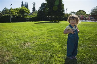Mixed race girl wearing overalls in park