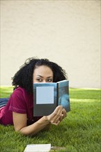 African woman laying in grass reading book