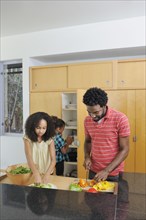 Father and daughters preparing food in kitchen