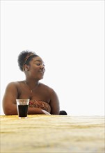 African American woman drinking soda at table
