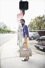 African American man carrying bag on sidewalk