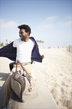 African American man removing shirt at beach