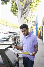African American man reading newspaper on sidewalk