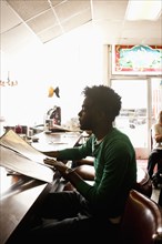 African American man reading menu at diner counter