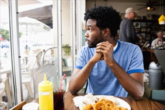 African American man looking out diner window