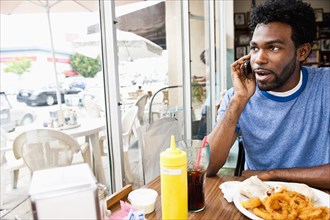 African American man talking on cell phone in diner