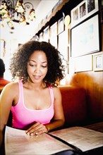 Smiling African American woman reading menu in diner