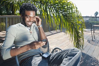 Black man listening to mp3 player on patio