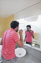 Black man in bathroom brushing teeth