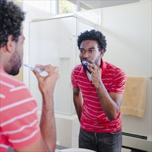 Black man in bathroom brushing teeth