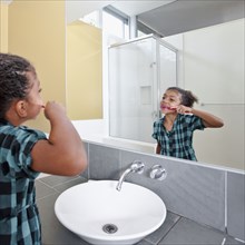 Mixed race girl in bathroom brushing teeth
