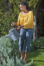 Black woman watering plants in garden