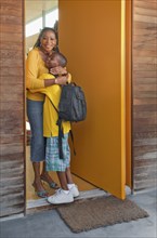 Black mother greeting son at front door