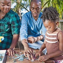 Black father and mother solving puzzle with child