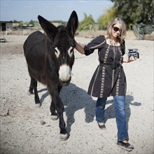 Caucasian woman walking with donkey