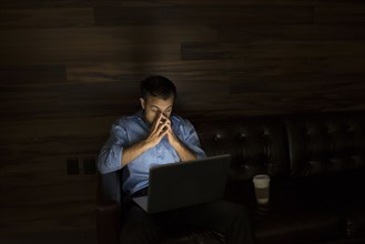 Businessman using laptop on sofa at night