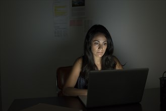 Businesswoman working at laptop at night