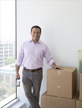 Hispanic businessman with cardboard boxes in new office