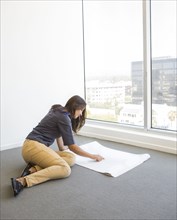 Woman reading blueprints in empty office