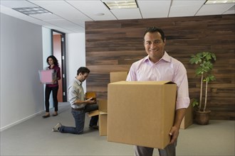 Hispanic businessman carrying cardboard box in office