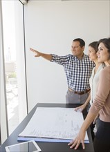 Business people examining blueprints in office